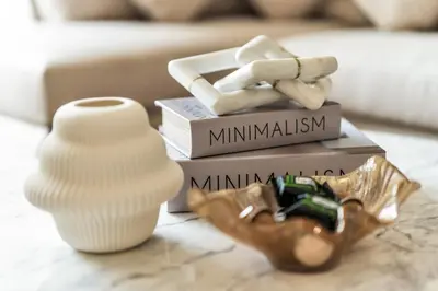 a table topped with books and a vase and a pile at Exec 1Bed with Balcony&Pool, 10mins to Downtown in Dubai