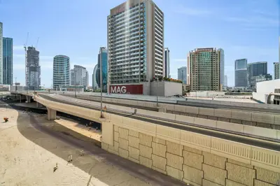 a bridge over a highway in a city with tall buildings at Exec 1Bed with Balcony&Pool, 10mins to Downtown in Dubai