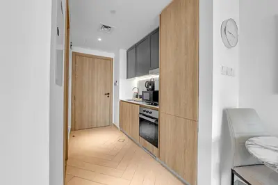 a kitchen with a door leading to a kitchen with a stove at Waves - Modern JVC Studio with Balcony in Dubai