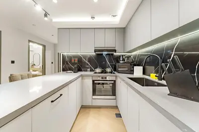 a kitchen with white cabinets and stainless steel appliances at JBR 3BR Palm Jumeirah & Sea Views, Pool & Gym Access in Dubai