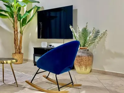 a blue chair in a living room with a tv at Motor City Norton Court Parking Pool in Dubai