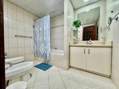 a bathroom with a sink and a toilet and a mirror at Motor City Norton Court Parking Pool in Dubai
