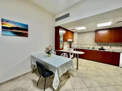 a dining room with a table and a kitchen at Motor City Norton Court Parking Pool in Dubai