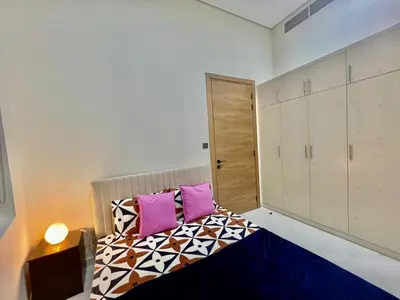 a bedroom with a bed with two pink pillows at Karama Palace Home in Dubai