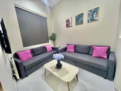 a living room with a blue couch and pink pillows at Karama Palace Home in Dubai