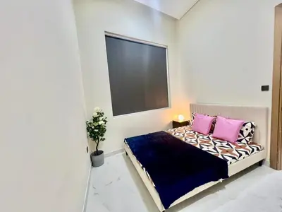 a bedroom with a bed with pink and purple pillows at Karama Palace Home in Dubai