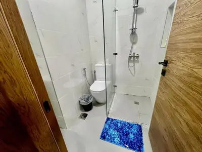 a bathroom with a shower and a toilet with a blue rug at Karama Palace Home in Dubai