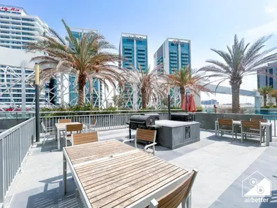 a patio with tables and chairs and palm trees at Your Fav Studio Getaway l Pool, Gym & Parking! in Dubai