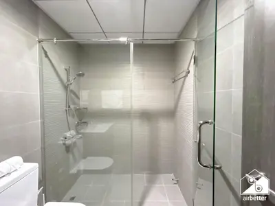 a bathroom with a glass shower with a toilet at Your Fav Studio Getaway l Pool, Gym & Parking! in Dubai
