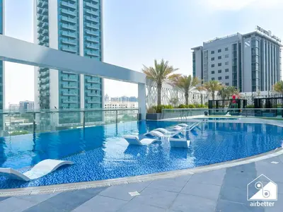 a large swimming pool with white chairs in a building at Your Fav Studio Getaway l Pool, Gym & Parking! in Dubai