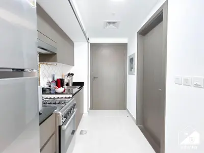 a white kitchen with a stove and a hallway at Your Fav Studio Getaway l Pool, Gym & Parking! in Dubai