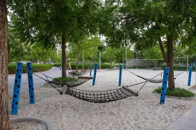 a playground with hammocks in a park with trees at Hills Parkhouse - Pool Gym Parks Mall and Burj Khalifa View in Dubai