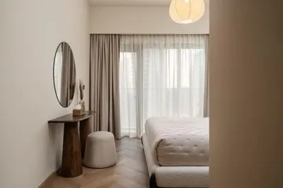 a bedroom with a bed and a mirror and a window at Seraya Residences at Burj Royale in Dubai