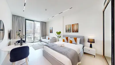 a white bedroom with a bed and a desk at Dusk By Binghatti - Dazzling Studio in JVC in Dubai