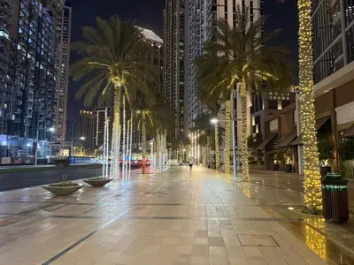 a street with palm trees in a city at night at Serenity Suite Stylish 2BR Pool & Fitness Perks in Dubai