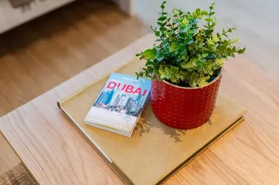 a potted plant and a book on a table at Cozy Marina Studio, Canal View with a Balcony in Dubai