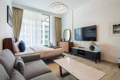 a bedroom with a bed and a tv and a couch at Brand New Studio with Pool View in The Grove by Iman, Dubai Hills in Dubai
