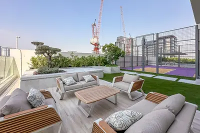 a patio with couches and chairs on a building at Brand New Studio with Pool View in The Grove by Iman, Dubai Hills in Dubai