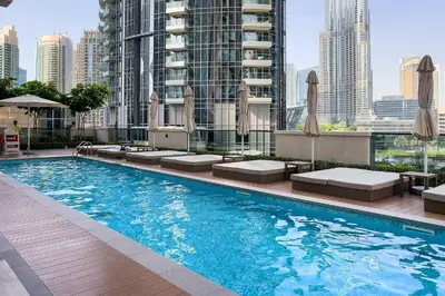 a swimming pool with chairs and umbrellas on a building at Burj View Stylish 3BR with Maids Room in Act One Tower Downtown in Dubai