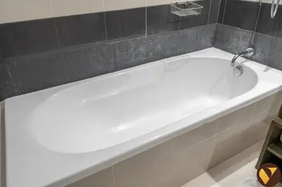 a white bath tub in a bathroom with black tiles at Vogue Downtown The Lofts near Burj Khalifa and Dubai Mall, Two Bedroom Apartment with Balcony and City Skyline View, Access to all Amenities in Dubai