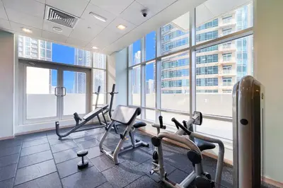 a gym with cardio equipment in a building with windows at Vogue Downtown The Lofts near Burj Khalifa and Dubai Mall, Two Bedroom Apartment with Balcony and City Skyline View, Access to all Amenities in Dubai