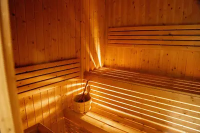 a wooden sauna with a bucket in the corner at Stylish 1BR Stay l Rooftop Pool, Sauna & Gym in Dubai