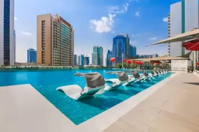 a row of chairs in a pool with a city skyline at Vogue Downtown Mag 318 near Burj Khalifa and Dubai Mall, Studio Apartment with Balcony, Canal and City View, Access to all Amenities in Dubai