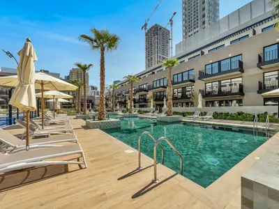 a swimming pool with lounge chairs and a building at New Luxury 2 Bedroom with Padel Gym Pool Cinema BBQ in Dubai