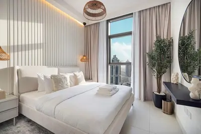 a white bedroom with a large bed and a large window at Mahogany 15 - 1BR 4 Guests - Walk to Burj Khalifa in Dubai