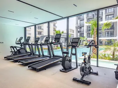 a row of treadmills in a gym with a pool at Modern Studio - Pool, Gym & Padel in Dubai
