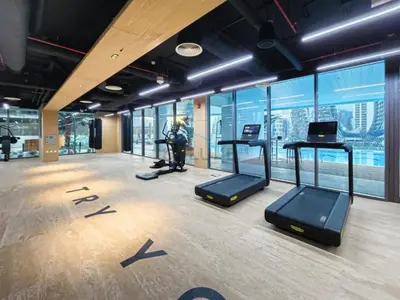 a gym with cardio equipment in a building with windows at Spacious Balcony with Private Jacuzzi and Stunning Views, Easy Public Transport Access, Terraces Marasi Drive, Business Bay by Deluxe Holiday Homes in Dubai
