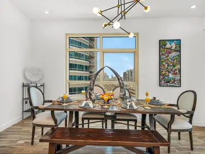 a dining room with a table and chairs and a window at 4 BHK Duplex - Marina & JBR - Iconic Dubai Skyline in Dubai