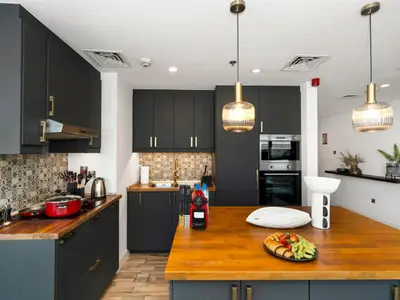 a kitchen with black cabinets and a wooden counter top at 4 BHK Duplex - Marina & JBR - Iconic Dubai Skyline in Dubai