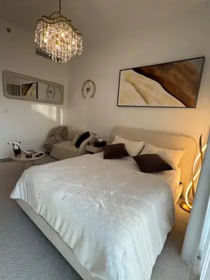 a bedroom with a white bed and a chandelier at Luxury Studio Burj Khalifa View in Dubai