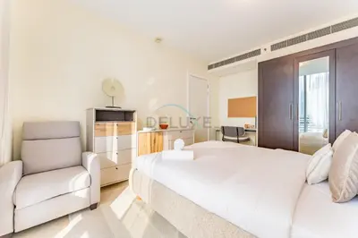 a bedroom with a white bed and a chair at Iconic Views of the Future Museum, Minutes from Metro & Key Attractions, Sky Gardens, DIFC by Deluxe Holiday Homes in Dubai