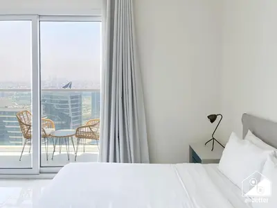 a bedroom with a bed and a balcony with a table at City-View Studio in AG Tower l Pool & Gym Access in Dubai