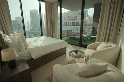 a bedroom with a bed and a chair and a large window at Private Jacuzzi 2BR Luxury Unit in Dubai