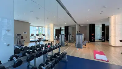 a gym with rows of exercise equipment in a building at Vogue Business Bay Damac Maison Prive near Burj Khalifa and Dubai Mall, One Bedroom Apartment with Balcony, Canal and City Skyline View, Access to all Amenities in Dubai