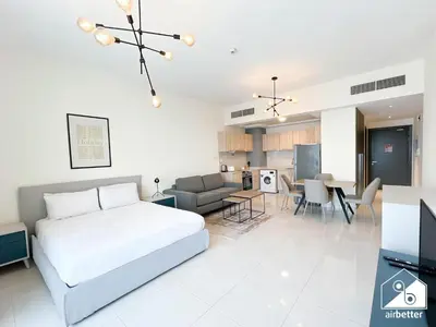 a white bedroom with a bed and a living room at Skyline Studio Escape l Balcony , Gym & Pool in Dubai