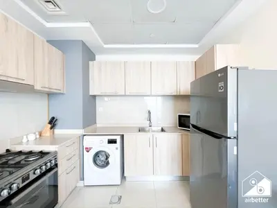 a kitchen with a refrigerator and a washer and dryer at Skyline Studio Escape l Balcony , Gym & Pool in Dubai