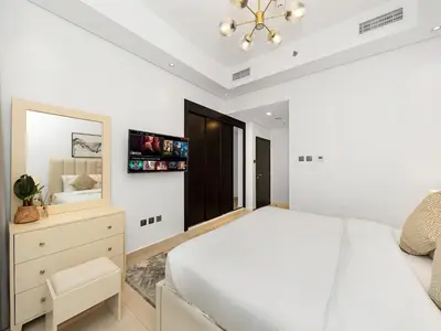 a white bedroom with a large bed and a tv at 5 Min to Dubai Mall Lux Stay Tennis Court in Dubai