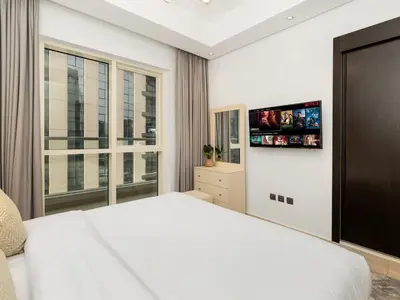 a bedroom with a white bed and a large window at 5 Min to Dubai Mall Lux Stay Tennis Court in Dubai