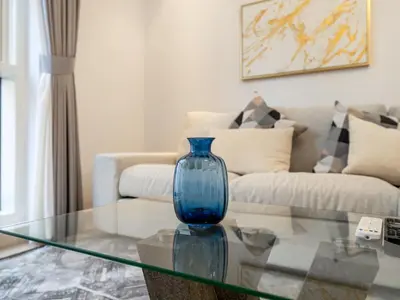 a blue vase sitting on a glass table in a living room at 5 Min to Dubai Mall Lux Stay Tennis Court in Dubai