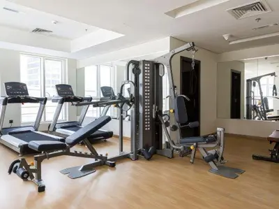 a gym with several tread machines in a room at 5 Min to Dubai Mall Lux Stay Tennis Court in Dubai
