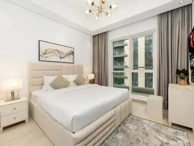 a white bedroom with a large bed and a window at 5 Min to Dubai Mall Lux Stay Tennis Court in Dubai