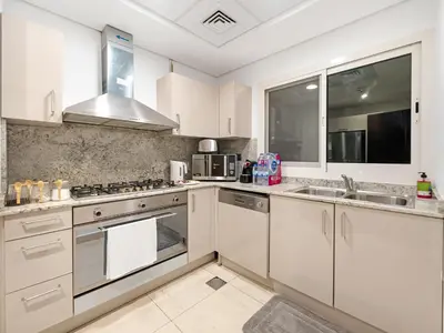 a kitchen with white cabinets and stainless steel appliances at 5 Min to Dubai Mall Lux Stay Tennis Court in Dubai