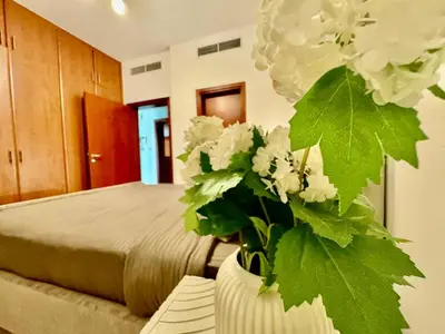 a bedroom with a bed with a vase with white flowers at The Greens very well-lit unit in Dubai