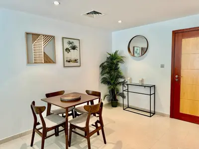 a dining room with a table and chairs and a mirror at The Greens very well-lit unit in Dubai