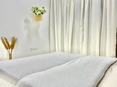 a bedroom with a bed with white sheets and a vase of flowers at 1 min to ADCB metro New home in Dubai