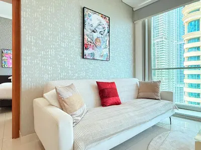 a living room with a white couch with red pillows at Ocean Heights New 2BDR with full Sea & Dubai Eye view in Marina by Simplex Home in Dubai